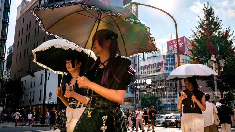 Pedestrians holding umbrellas walk on a hot day amid a heatwave in Tokyo’s Shinjuku district on August 30, 2025. - Philip FONG / AFP