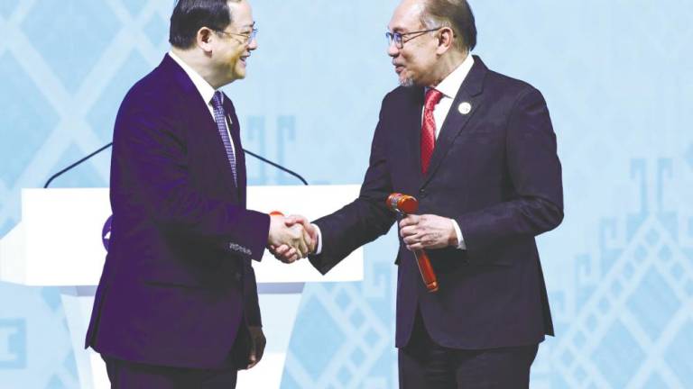 Prime Minister Datuk Seri Anwar Ibrahim holds the ceremonial gavel as he shakes hands with Laos Prime Minister Sonexay Siphandone, who handed over his country’s chairmanship to Malaysia. – REUTERSPIC