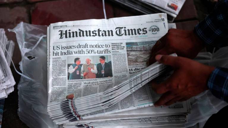 A hawker sorts copies of the latest edition of Hindustan Times, with the lead story on U.S. tariffs on most Indian goods, in New Delhi, India, August 27, 2025. - REUTERSPIX