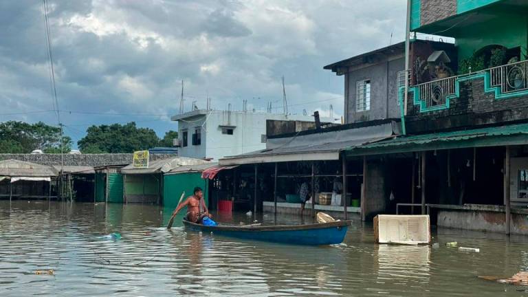 This photo taken on October 4, 2025 shows a resident paddling a wooden boat past flooded houses near an inundated river after a dam released waters due to heavy rains brought by Tropical Storm Matmo in Tuguegarao City. - John Dimain / AFP