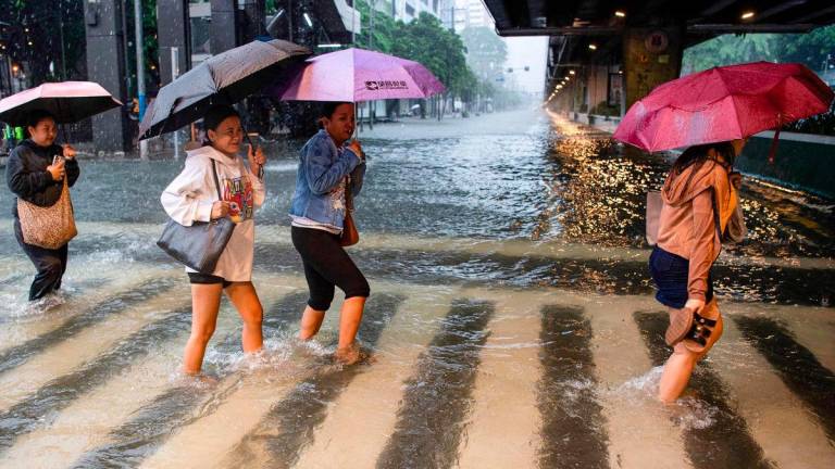 A file photo taken on July 22, 2025, shows pedestrians wading through a flooded street in Manila. - AFP