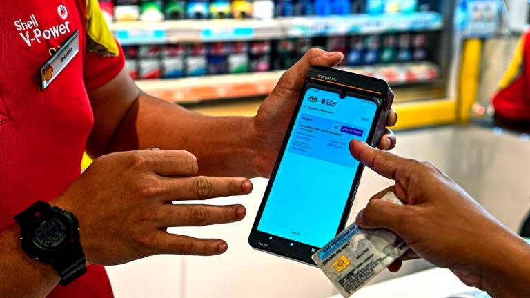 Pegawai Tentera Lt Kol Muhammad Afifi Azham Mohd (kanan) menggunakan MyTentera di kaunter pembayaran untuk pengisian petrol RON95 pada harga RM1.99 seliter berbanding RM2.05 seliter di stesen Shell Jalan Sunggala, menerusi inisiatif BUDI MADANI RON95 (BUDI95) yang bermula hari ini. - fotoBERNAMA
