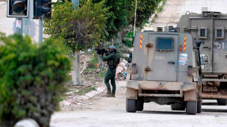 An Israeli soldier takes aim at the entrance of the occupied West Bank refugee camp of Tulkarem, during an ongoing military raid - AFPpix