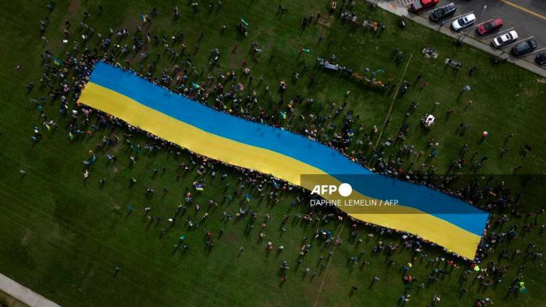 This aerial view shows protesters holding a giant Ukrainian flag in Anchorage, Alaska, on August 15, 2025 during a US-Russia summit at nearby Joint Base Elmendorf-Richardson. - AFP