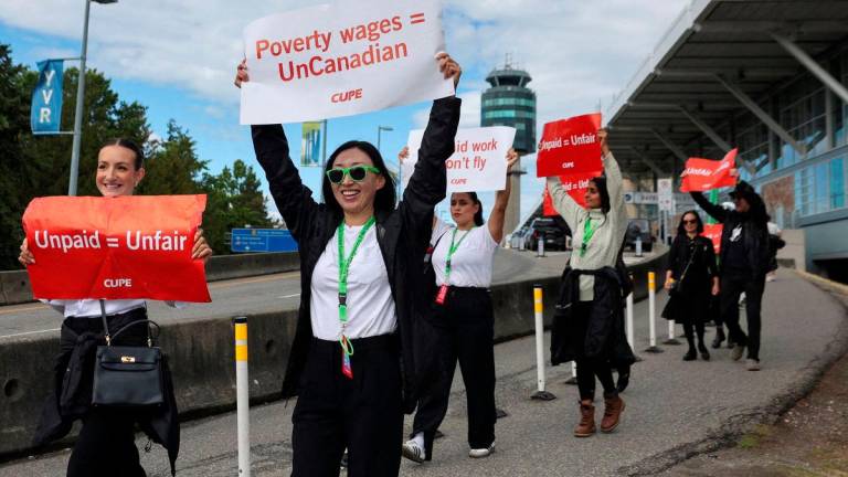 Demonstrators hold placards on the day the strike begins, after the union representing more than 10,000 of Air Canada’s flight attendants failed to reach an agreement with the airline, at Vancouver International Airport in Richmond, British Columbia, Canada, August 16, 2025. REUTERS/Chris Helgren