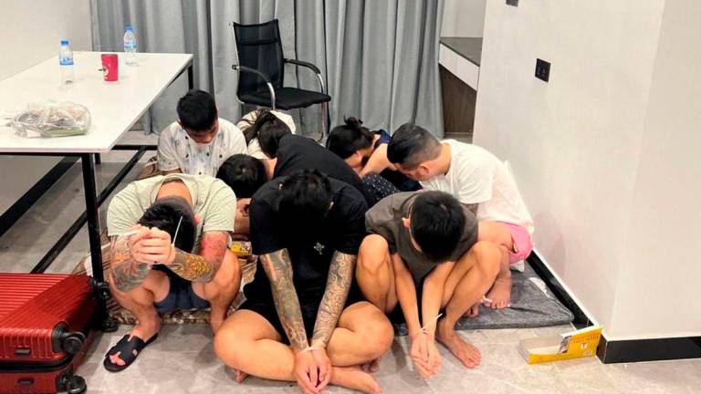 This pool photo taken on July 14, 2025 and released on July 16 by Agence Kampuchea Presse (AKP) shows suspects with their hands ziptied after being detained during a raid on a scam centre in Phnom Penh. (Photo by POOL / AFP)