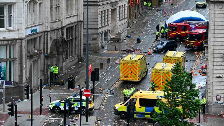 Police officers cover with an inflatable tent, behind a firefighter vehicle, the tents delimiting the scene of an incident in Water Street, on the sidelines of an open-top bus victory parade for Liverpool’s Premier League title win, in Liverpool, north-west England on May 26, 2025