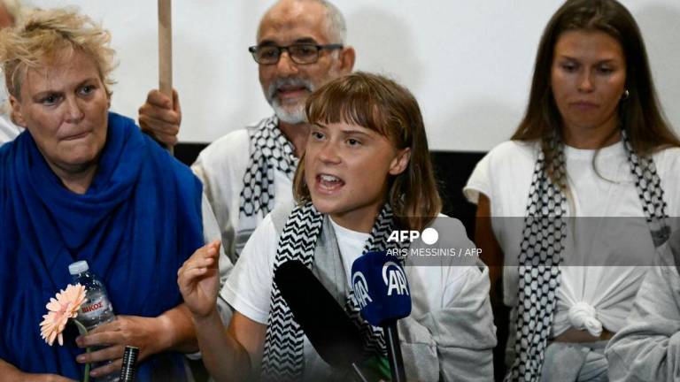 Swedish climate campaigner Greta Thunberg (C) delivers remarks upon arrival alongside activists who were sailing aboard vessels from the Gaza-bound aid flotilla before being stopped and detained by Israeli forces, greeted by a crowd of supporters, at the arrivals area of Athens International Airport on October 6, 2025. (Photo by Aris MESSINIS / AFP)
