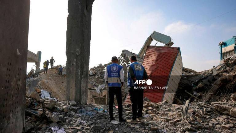 UN workers stand amid the rubble of an UNRWA aid supply depot and shelter, heavily damaged in an overnight Israeli strike in Jabalia in the northern Gaza Strip on May 10, 2025. - BASHAR TALEB / AFP