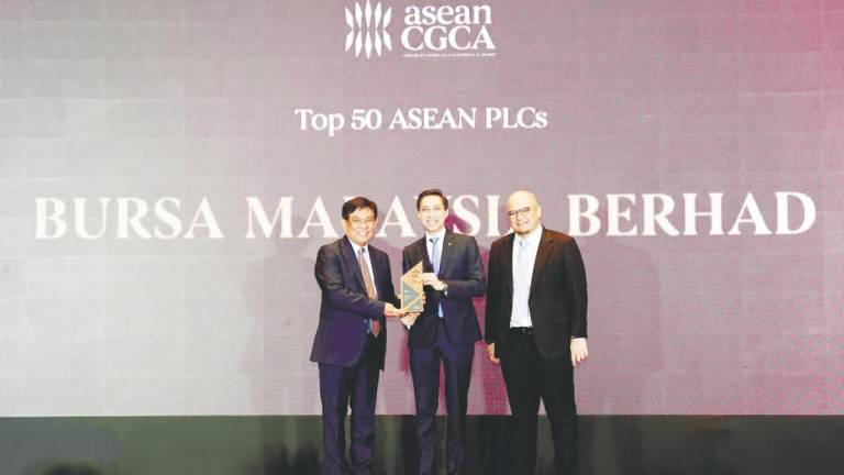 Fad’l (centre) receiving the award on behalf of Bursa Malaysia from Asean Capital Markets Forum working group on corporate governance and Philippines Securities and Exchange Commission chair Francisco Edralin Lim. On the right is Minority Shareholders Watch Group CEO Dr Ismet Yusoff.