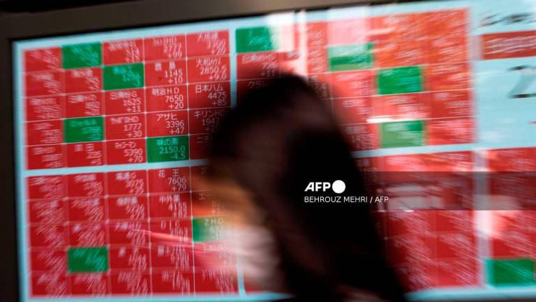 A pedestrian walks past an electronic board displaying share prices on the Tokyo Stock Exchange in Tokyo on November 4, 2020, as Asian markets react to early predictions following the US presidential election. - AFP