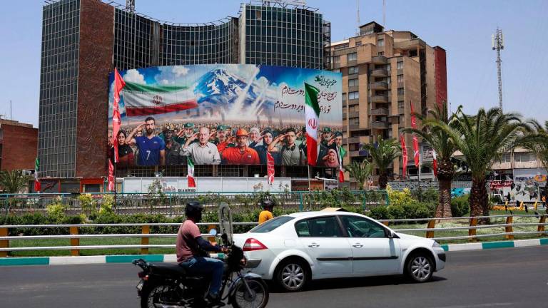 A banner bearing a painting that represents various categories of the Iranian society is deployed against the facade of a building in Tehran, with a message that reads in Farsi: “ we are all soldiers of Iran”, on June 22, 2025. - AFPpix