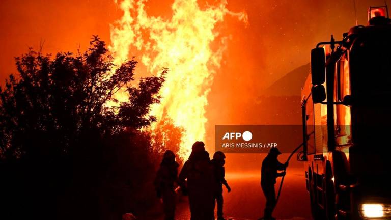 Firefighters work to extinguish a wildfire near the city of Patras, western Greece on August 13, 2025. Greece on August 13, 2025 battled to contain more than 20 wildfires including one menacing its third-largest city Patras as a heatwave stoked blazes and forced the evacuation of thousands in southern Europe -Photo by Aris MESSINIS / AFP