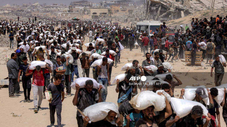 People walk with sacks of flour delivered after trucks carrying humanitarian aid entered northern Gaza on July 27, 2025 coming from the Zikim border crossing. - AFP