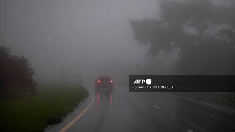 Car drive through heavy fog as category 3 Hurricane Erin leaves the region in Cayey, Puerto Rico on August 16, 2025. - Ricardo ARDUENGO / AFP