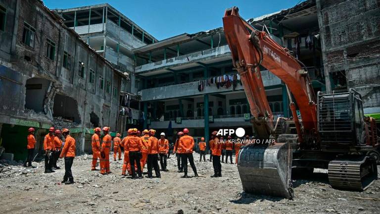 Rescue team members from the National Search and Rescue Agency (BASARNAS) gather after a closing ceremony marking the end of debris removal and search operations at the site of the collapsed Al Khoziny Islamic boarding school in Sidoarjo, East Java, on October 7, 2025. - JUNI KRISWANTO / AFP