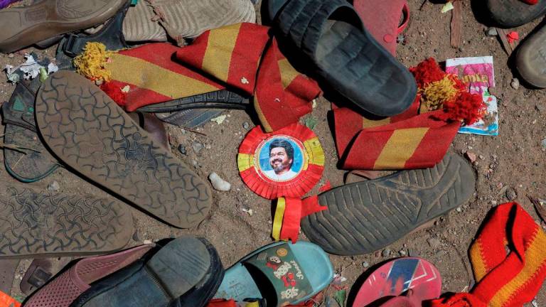 A badge with picture of Vijay, actor and politician, lies amid footwears and other belongings left by attendees at the site of a stampede incident during an election campaign rally held by Tamilaga Vettri Kazhagam party, in Karur district of Tamil Nadu, India, September 28, 2025. - REUTERS