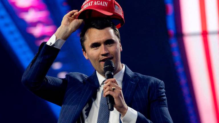 FILE PHOTO: Charlie Kirk, Turning Point USA founder, puts on a MAGA hat during the AmericaFest 2024 conference sponsored by conservative group Turning Point in Phoenix, Arizona, U.S. December 19, 2024. REUTERS/Cheney Orr/File Photo