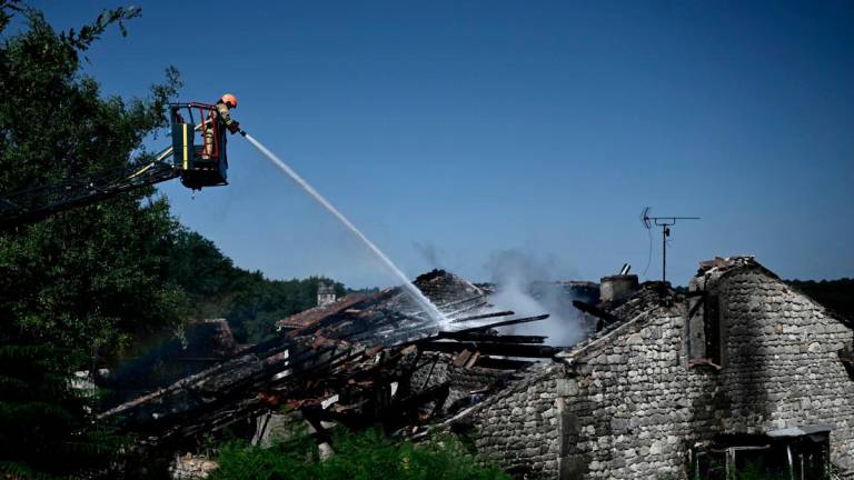 A firefighter works at the site of a French holiday cottage gite for disabled adults where a fire broke out leaving one person dead and four people still missing in Montmoreau, south-western France, on July 28, 2025. (Photo by Philippe LOPEZ / AFP)