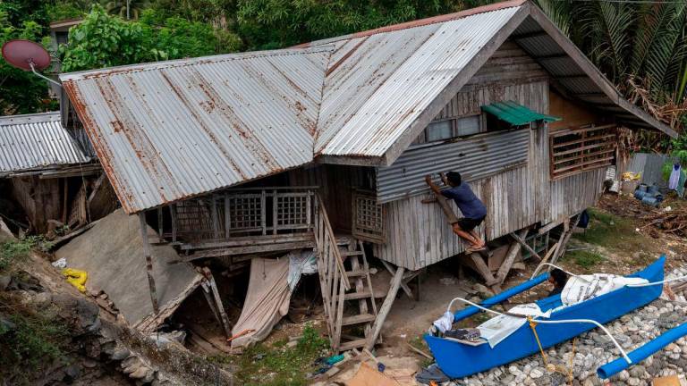 Saudara-mara Manuel Mandabon, pemilik rumah yang rosak berusia 87 tahun, menutup tingkap kediamannya selepas gempa bumi bermagnitud 7.4 melanda Manay, Davao Oriental, Filipina, pada 11 Oktober 2025. - REUTERS