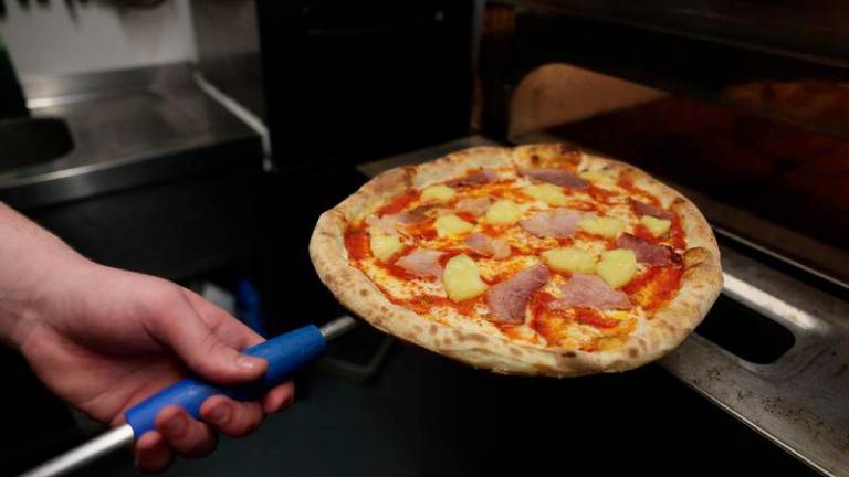 Chef Oliver Bardwell prepares a Hawaiian, ham, and pineapple-topped pizza at Lupa Pizza restaurant in Norwich, Britain, January 23, 2025. - REUTERSPIX