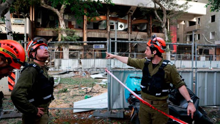 A rescuer worker gestures near a damaged building in the Israeli city of Tel Aviv following an Iranian missile attack on June 16, 2025. Israel’s Magen David Adom emergency service said on June 16 that three people were killed and 74 wounded following Iran’s latest missile attack.