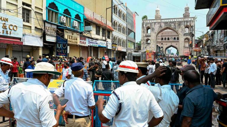Fire personnel and police stand outside the Krishna Pearls building (blue-colored) that caught fire in Hyderabad on May 18, 2025. AFPpix