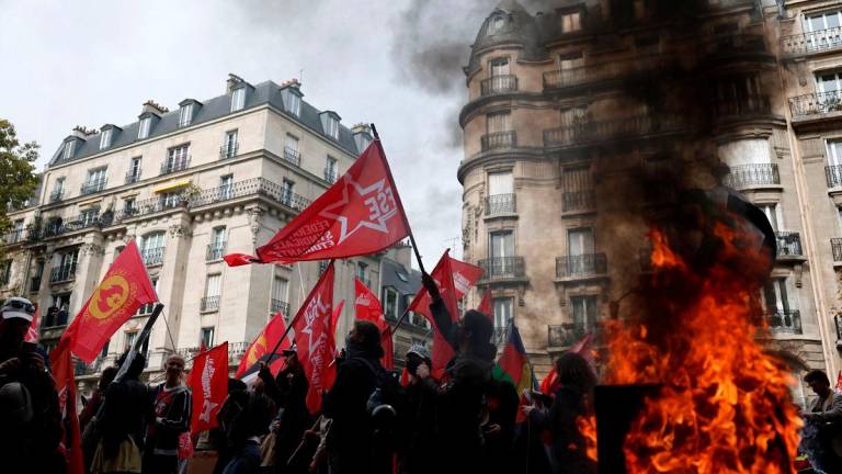 Protesters holding flags walk past a burning garbage bin during a demonstration in Paris as part of a day of nationwide strikes and protests against the government and possible austerity cuts in France, October 2, 2025. REUTERS/Benoit Tessier