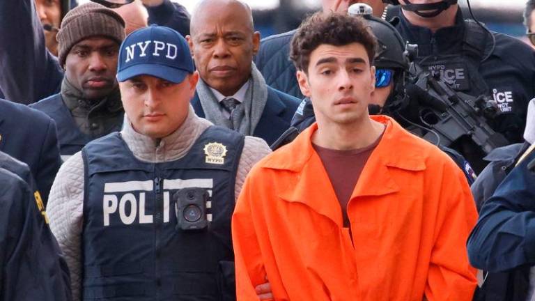 Luigi Mangione, the suspect in the murder of UnitedHealth Group executive Brian Thompson, arrives at a helicopter pad after being extradited from Pennsylvania, as New York Mayor Eric Adams walks behind him, in New York, U.S. Reuterspix