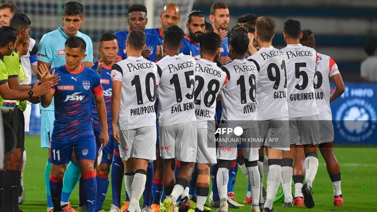 Players of Bengaluru Football Club and North East United Football Club greet each other before the commencement of the Indian Super League (ISL) 2022-23 football tournament, between Bengaluru Football Club and North East United Football Club played at the Shri Kanteerava Stadium in Bangalore on October 8, 2022. - MANJUNATH KIRAN / AFP