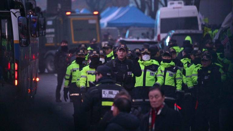 Police are seen between their parked vehicles on the road outside the residence of South Korea's impeached President Yoon Suk Yeol in Seoul early on January 6, 2025. - AFPPIX