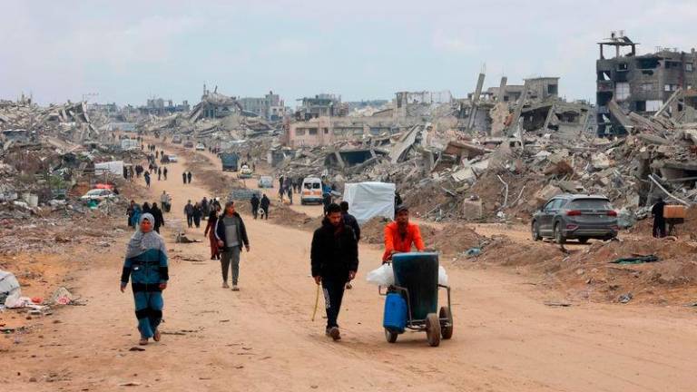 Palestinians walk past collapsed buildings along Saftawi street in Jabalia in the northern Gaza Strip - AFPpix. Pix for visual purposes.