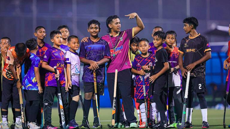 Faizal Saari (centre) during a training clinic at Taman Daya, Johor recently. – Region Sport Hockey Club