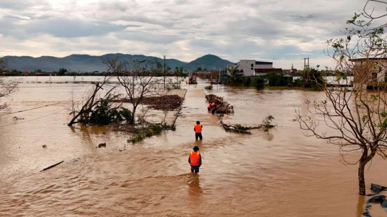 An aerial photo shows rescue workers walking through flood waters after typhoon Bualoi passed over Lam Thanh commune in Nghe An province on September 30, 2025. - Phan Duy / AFP
