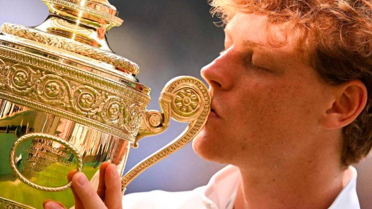 Italy’s Jannik Sinner kisses the winner’s trophy as he poses for pictures following his victory against Spain’s Carlos Alcaraz at the end of their men’s singles final tennis match on the fourteenth day of the 2025 Wimbledon Championships at The All England Lawn Tennis and Croquet Club in Wimbledon, southwest London, on July 13, 2025. - AFP