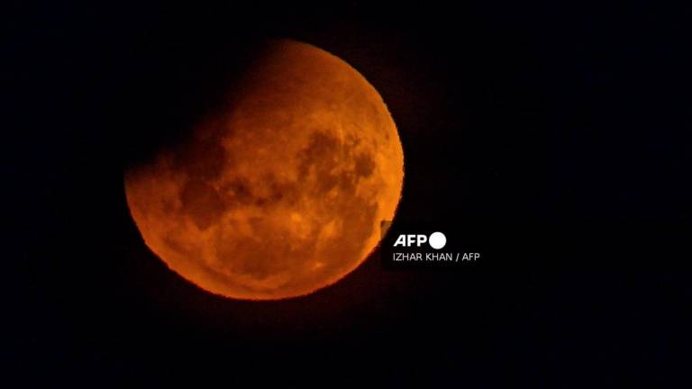 A full moon, also known as the Blood Moon, is seen during a partial eclipse in the sky over Lake George near the Australian capital city of Canberra on March 14, 2025. Stargazers across a swathe of the world marvelled at a dramatic red Blood Moon during a rare total lunar eclipse in the early hours of March 14. - AFPPIX