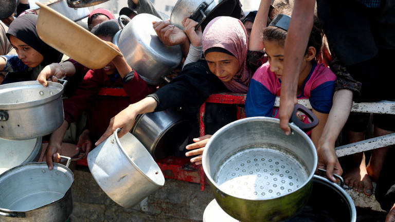 Palestinians wait to receive food from a charity kitchen, amid a hunger crisis, in Gaza City, July 26, 2025. - REUTERS