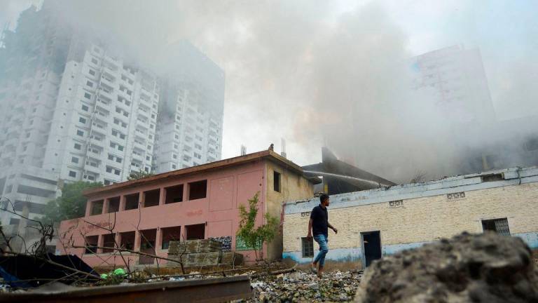 A person walks outside a fireworks warehouse as smoke rises after an explosion, in Karachi, Pakistan August 21, 2025. REUTERS/Imran Ali