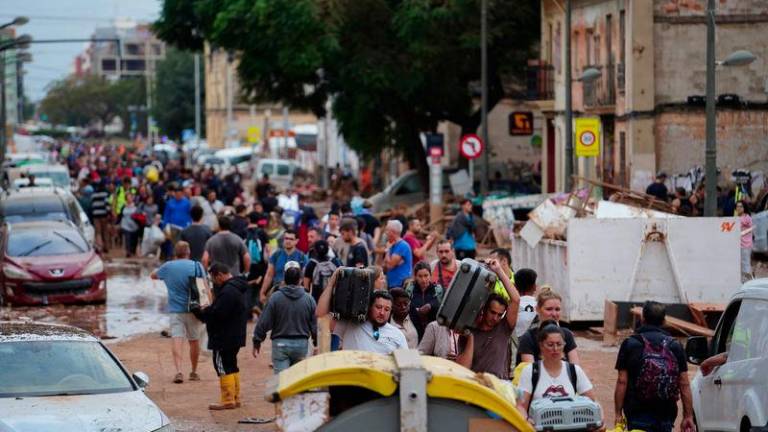 Residents walk in the street while transporting belongings following deadly flash floods in La Torre, south of Valencia, eastern Spain, on October 31, 2024. - AFPPIX