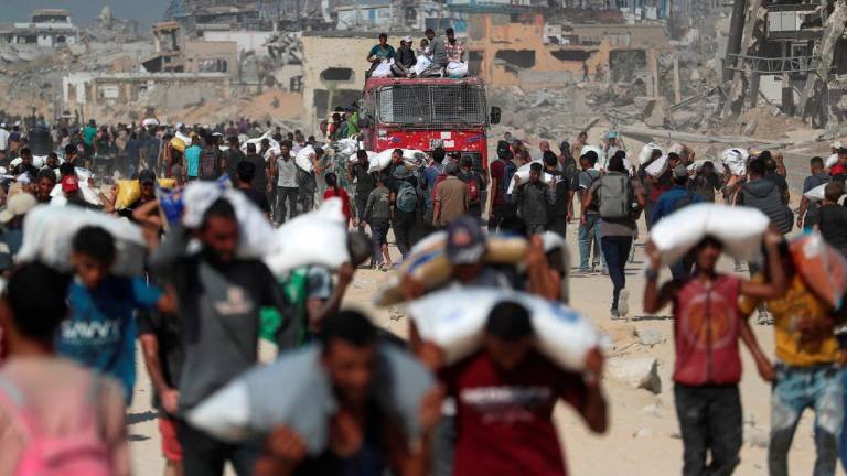 Palestinians carry aid supplies that entered Gaza through Israel, in Beit Lahia, northern Gaza Strip, August 2, 2025. - REUTERS/Mahmoud Issa