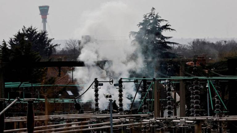 Smoke rises from the area of an electrical substation, with a control tower from the Heathrow International Airport on the background, after a fire there wiped out the power at the airport, in Hayes, London, Britain, March 21, 2025. - REUTERS/Carlos Jasso/File Photo