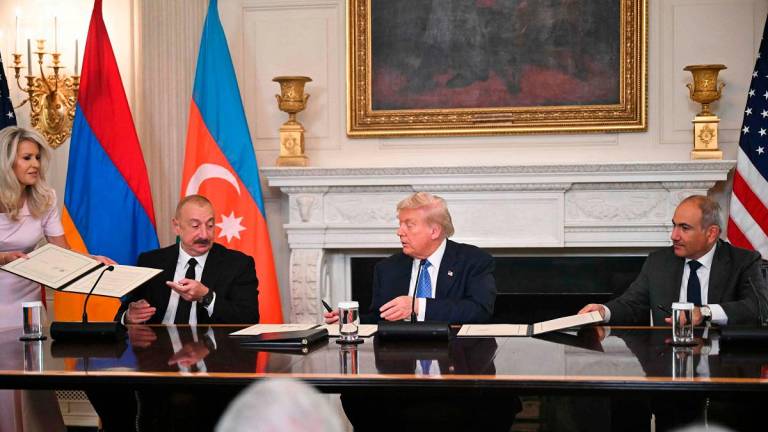 US President Donald Trump (C), Azerbaijani President Ilham Aliyev (L) and Armenian Prime Minister Nikol Pashinyan sign an agreement in the State Dining Room of the White House in Washington, DC, on August 8, 2025. US President Donald Trump said Friday that Armenia and Azerbaijan were committed to a permanent peace as he hosted a White House summit with the leaders of the two South Caucasus nations, which have fought for decades. - ANDREW CABALLERO-REYNOLDS / AFP