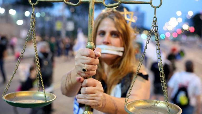 A demonstrator carrying a scale attends an anti-government protest calling for action to secure the release of Israeli hostages held captive since the October 7 attacks by Palestinian militants in the Gaza Strip and to end the war, in front of the Israeli Defence Ministry in the coastal city of Tel Aviv on May 3, 2025. AFPpix