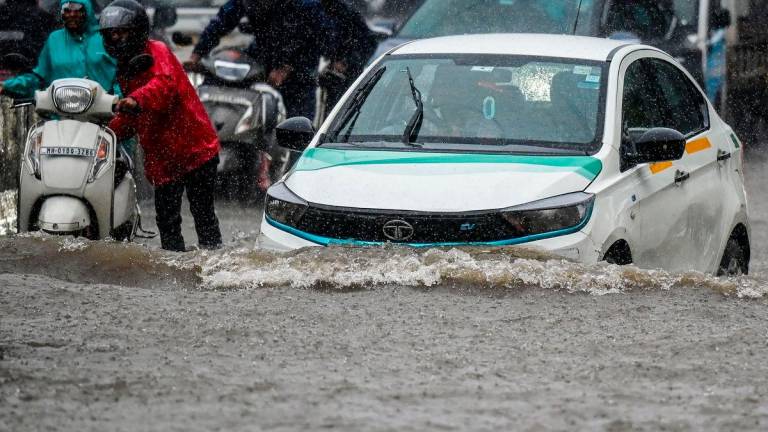 Vehicles wade through a flooded street during heavy rain showers in Mumbai on August 18, 2025. (Photo by Punit PARANJPE / AFP)