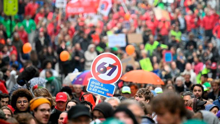 Protesters hold a slogan reading “Right to have pension at the age of 65” as they take part in a demonstration during a national day of action against the austerity of the federal Arizona government, in Brussels on October 14, 2025. - NICOLAS TUCAT / AFP