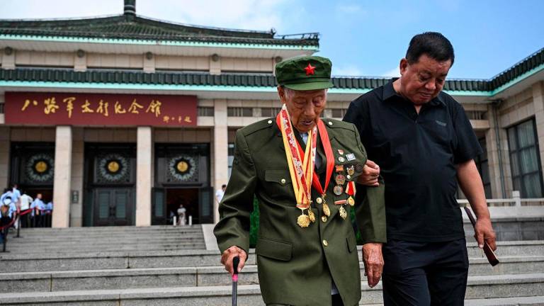This photo taken on July 23, 2025 shows Li Jinshui (L), a veteran of the Second Sino-Japanese War, walking after an interview with the media at the Eighth Route Army Taihang Memorial Hall in Wuxiang, in China’s northern Shanxi province. - HECTOR RETAMAL / AFP