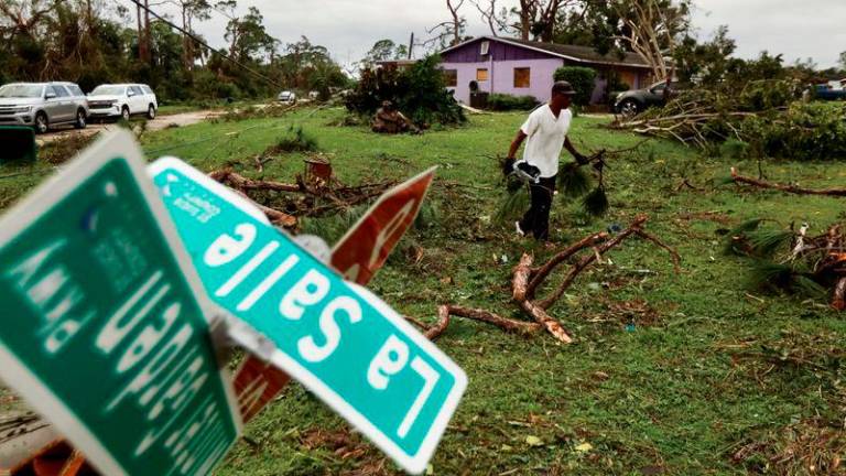 A man picks up debris left by a tornado in a zone affected by Hurricane Milton, in Lakewood Park, Florida. REUTERSPIX