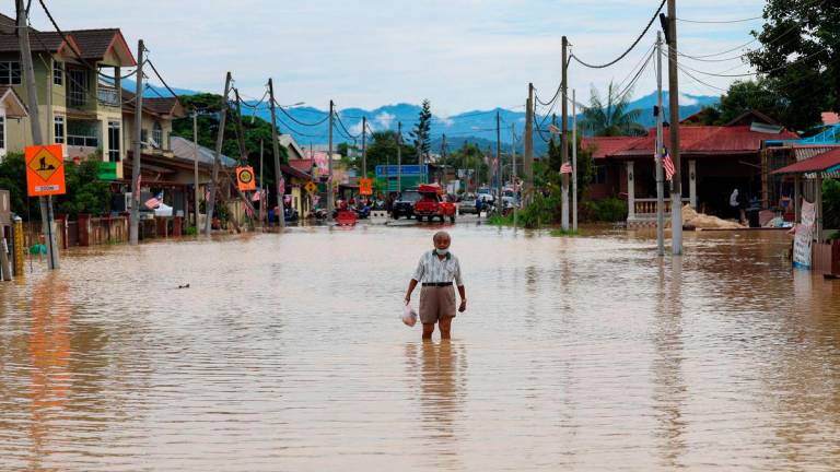 Seorang warga emas meranduk banjir yang menenggelamkan jalan utama Hulu Langat di Kampung Sungai Serai ketika tinjauan Bernama hari ini- BERNAMA