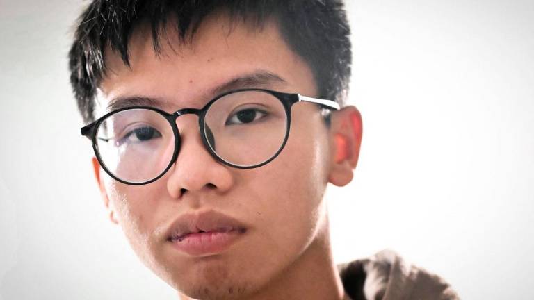 (FILES) Hong Kong democracy activist Tony Chung poses in a bedroom in Britain on December 29, 2023 after fleeing Hong Kong. Hong Kong democracy activist Tony Chung, who once called for the city’s independence and was the youngest person to be jailed under its national security law, announced on August 17, 2025 he has been granted asylum in the UK (Photo by Ben Stansall / AFP)