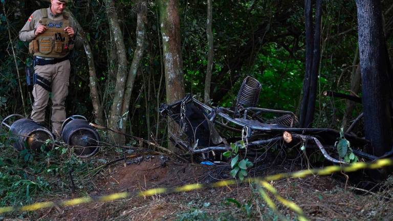 A military police officer stands next to the wreckage of a hot air balloon that caught fire and crashed with 21 people on board in Praia Grande, Santa Catarina State, southern Brazil, on June 21, 2025. At least eight people were killed and 13 other were injured after the basket plummeted dozens of meters to the ground in flames in southern Brazil, the governor of Santa Catarina Jorginho Mello reported. - SILVIO AVILA / AFP